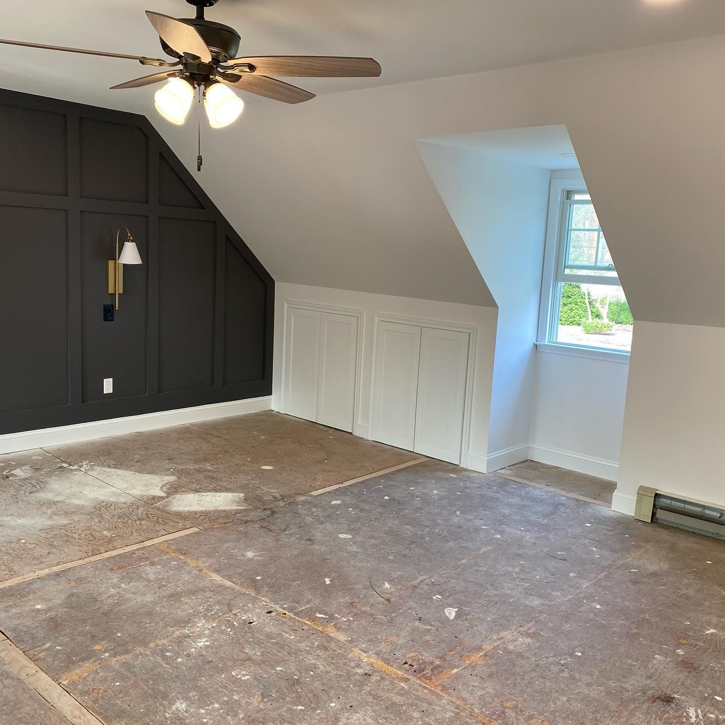 An empty room with a ceiling fan and a window.