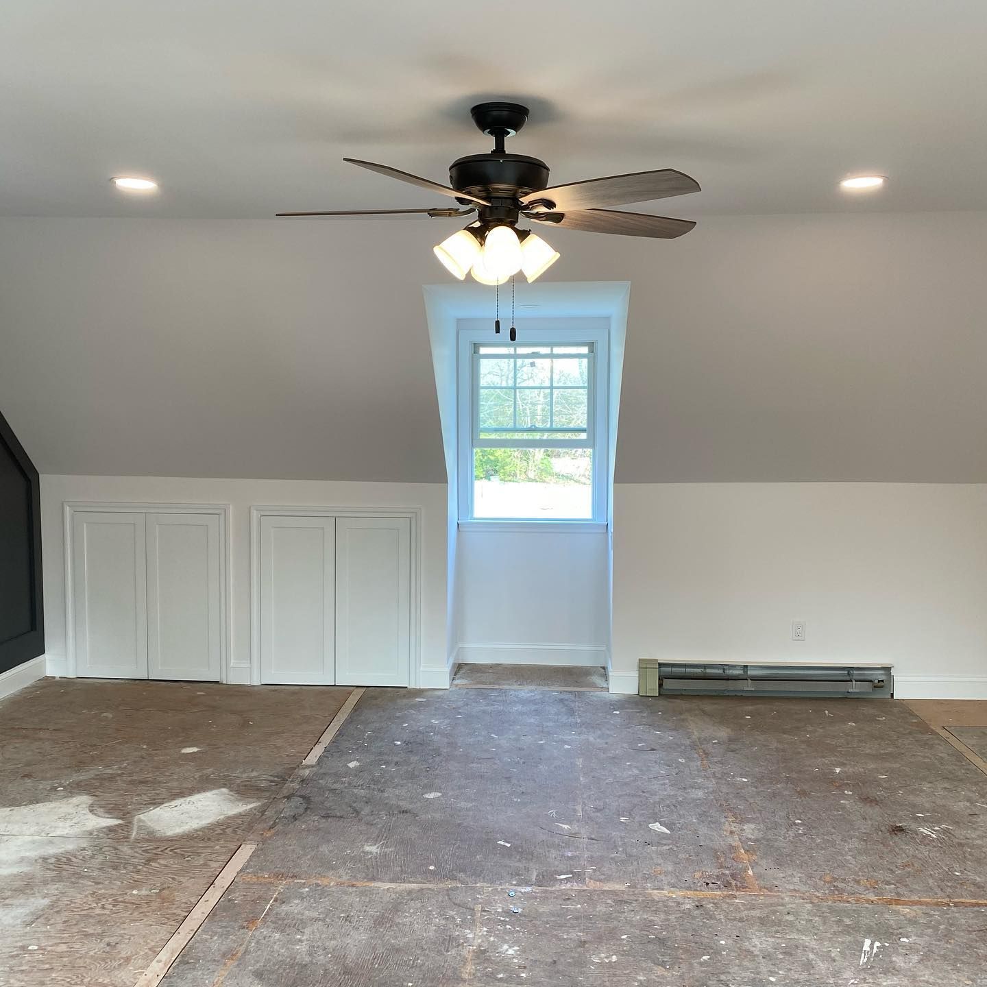 An empty room with a ceiling fan and a window