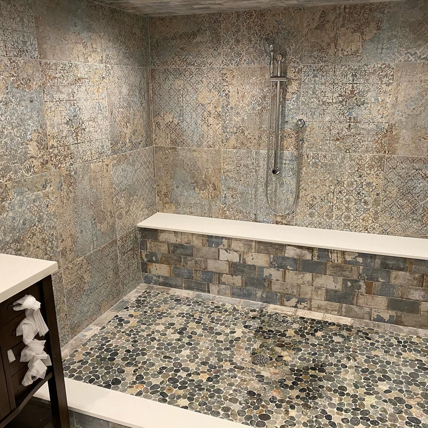 A bathroom with a walk in shower and a bench.