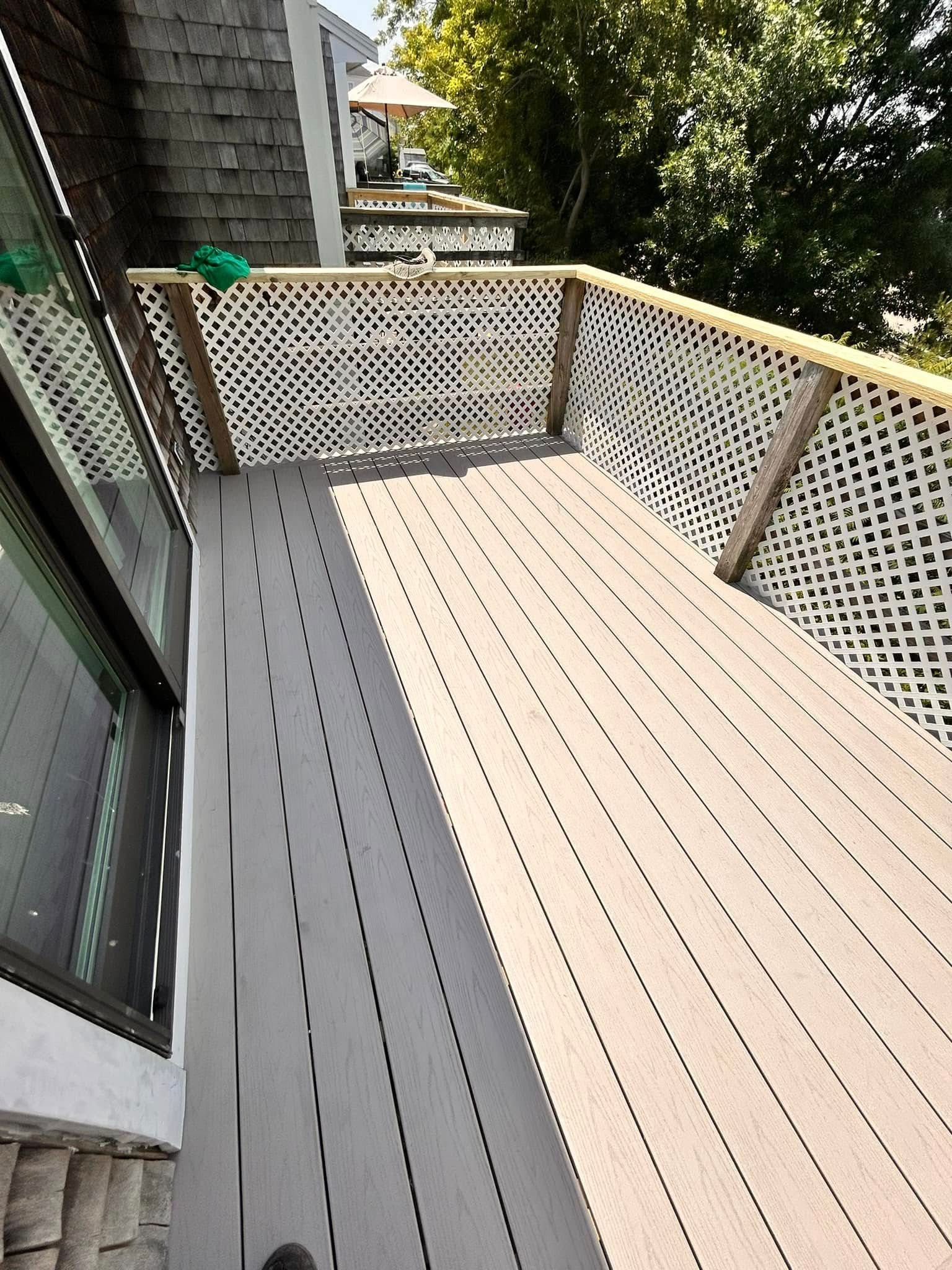 Gray deck with lattice railing, next to a window, in an outdoor setting.