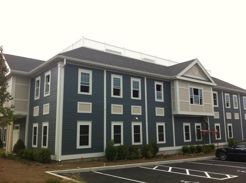 Two-story building with blue siding and white trim. Parking lot in front.