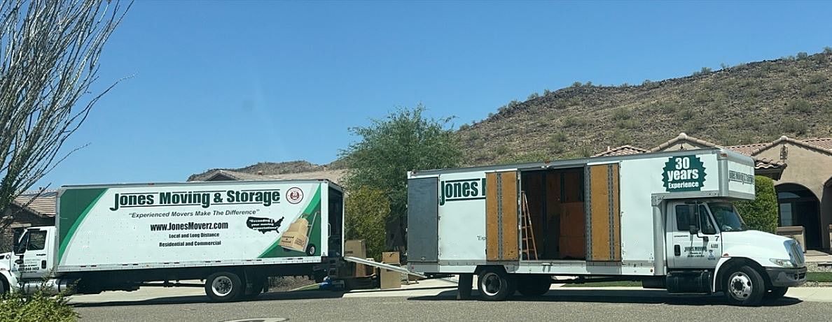 Two moving trucks parked in front of a house on a sunny day.
