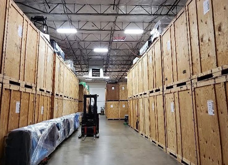 Warehouse with rows of wooden storage units and a forklift.