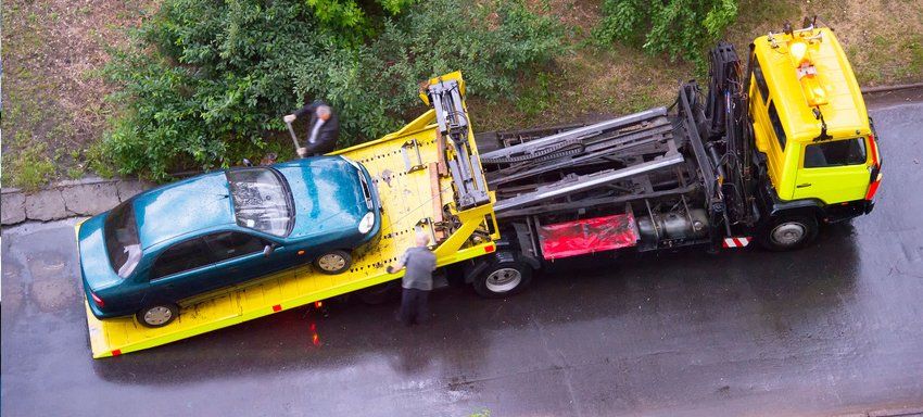 Car being towed by a yellow truck
