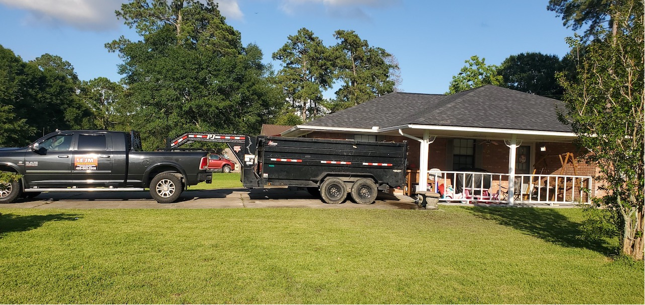 A truck is pulling a trailer in front of a house.