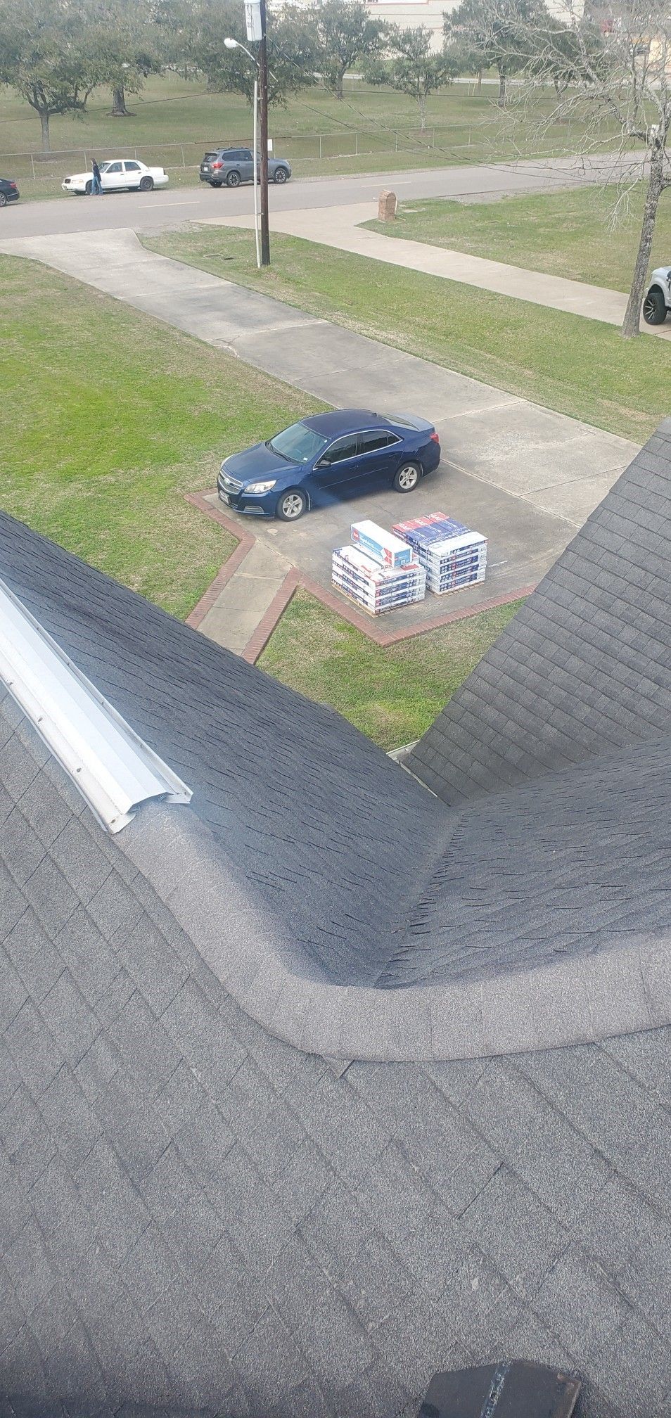 A car is parked on the side of the road next to a stack of boxes.