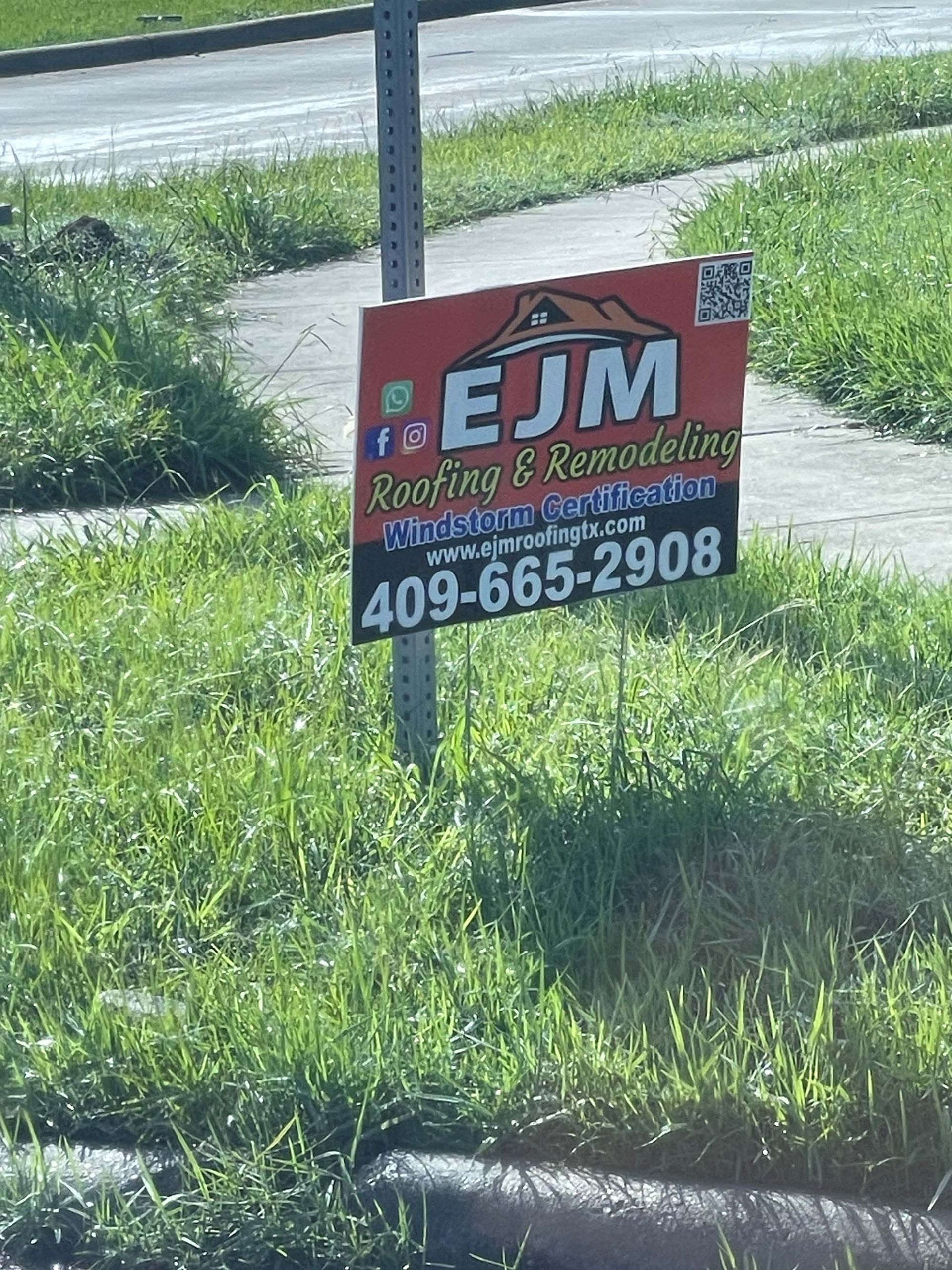 A sign for ejm roofing and remodeling is in the grass