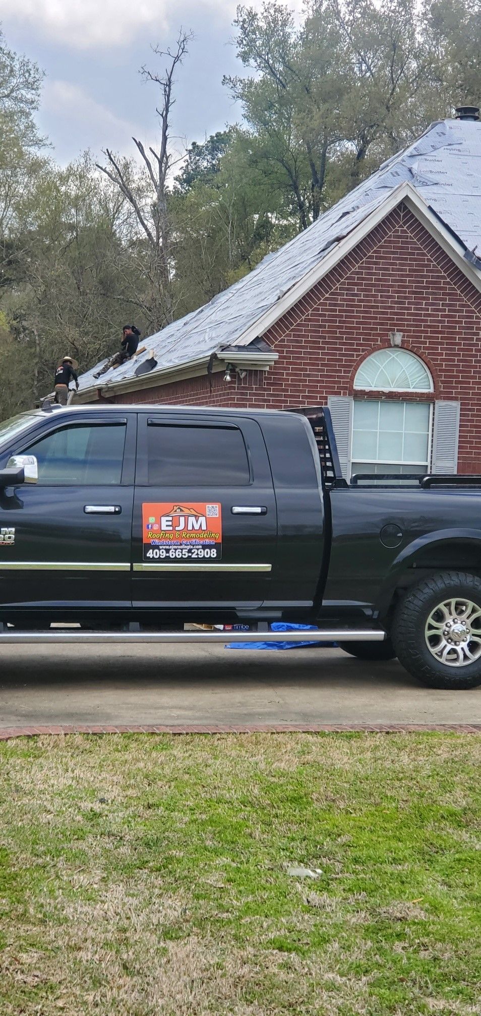 A black truck is parked in front of a brick house.