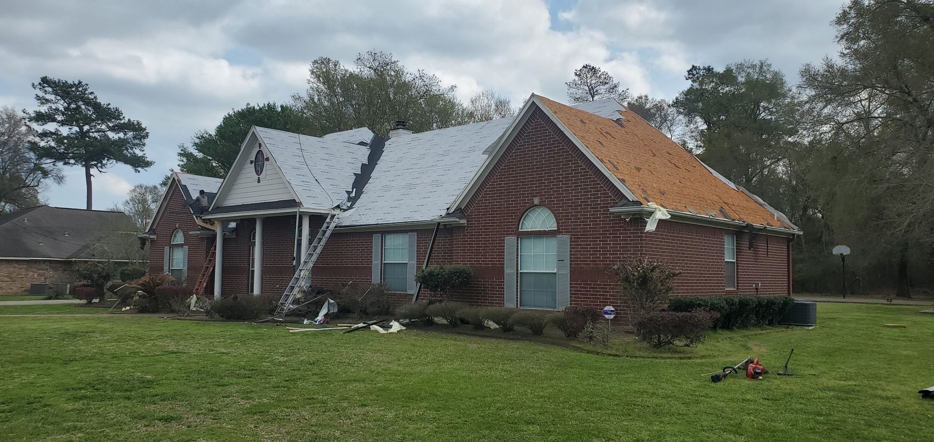 A brick house with a roof that has been damaged by a storm.