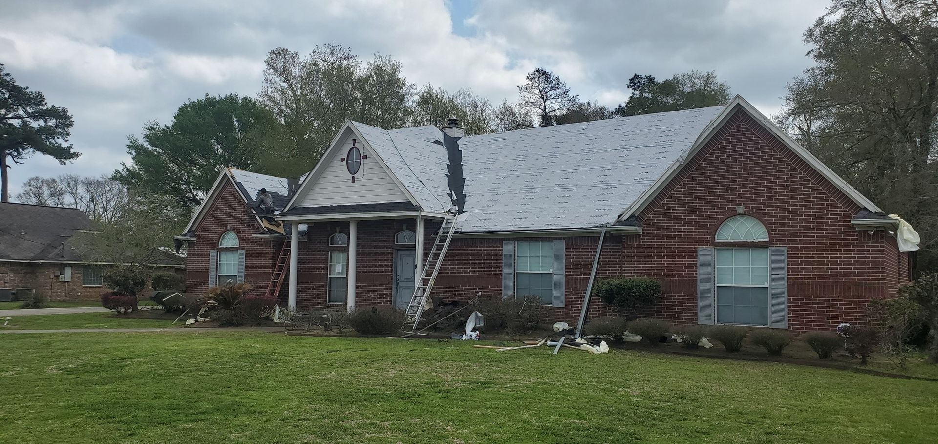 A brick house with a white roof is sitting on top of a lush green lawn.