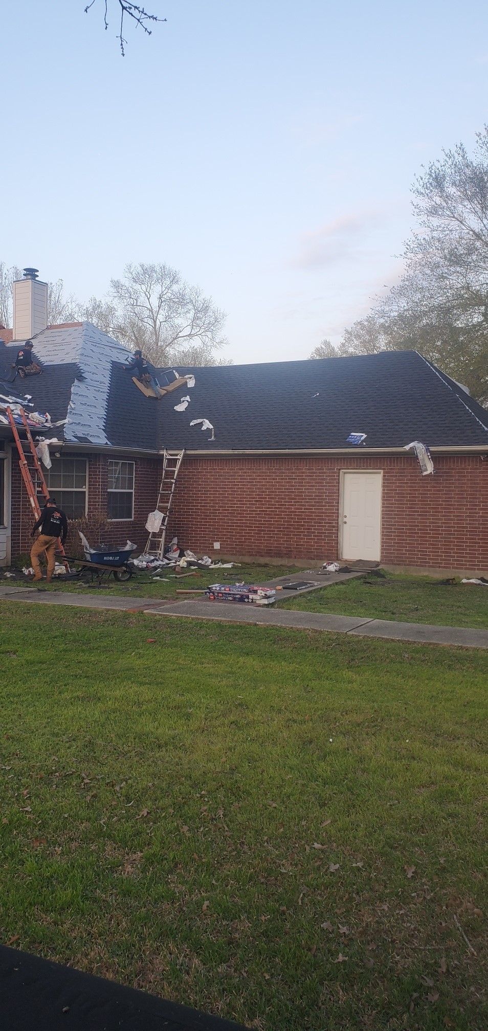 A brick house with a black roof is being remodeled.