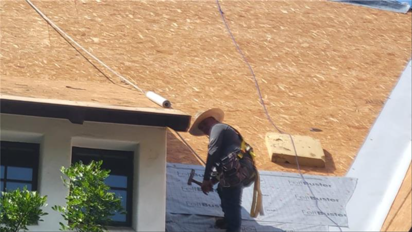 A man is working on a roof with a hammer.