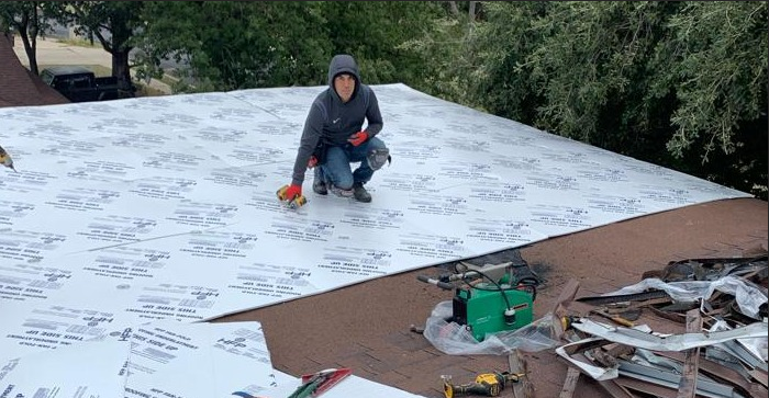 A man is kneeling on top of a roof.