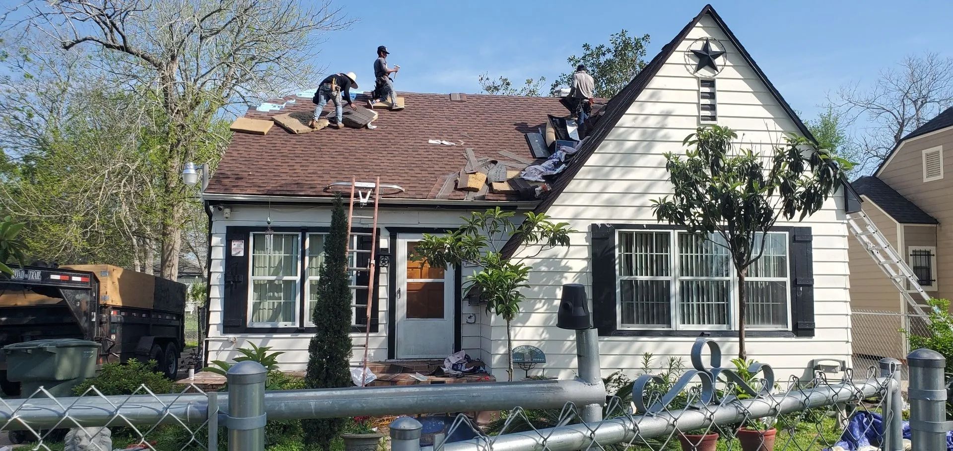 A white house with a brown roof is being remodeled.