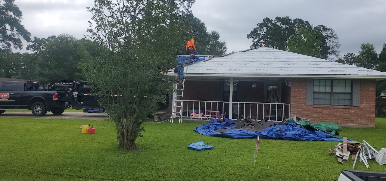A man is standing on top of a roof of a house.