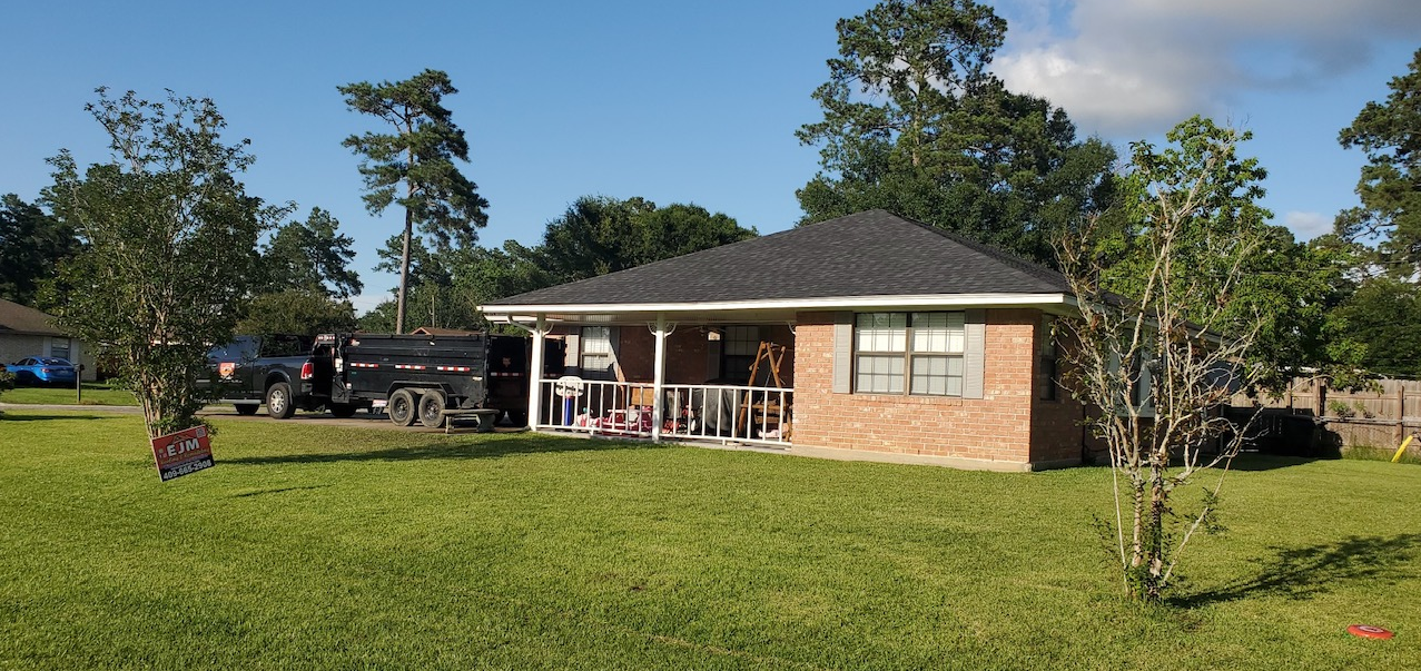 A small brick house with a porch and a truck parked in front of it.