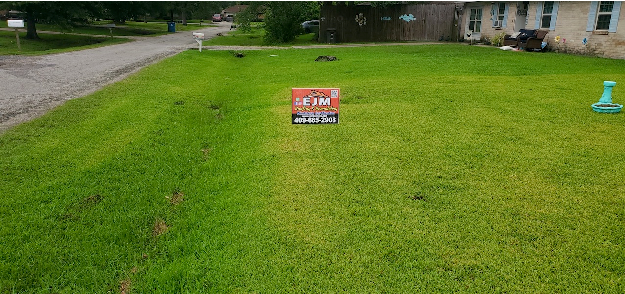 A lot for sale sign is sitting in the middle of a lush green lawn.