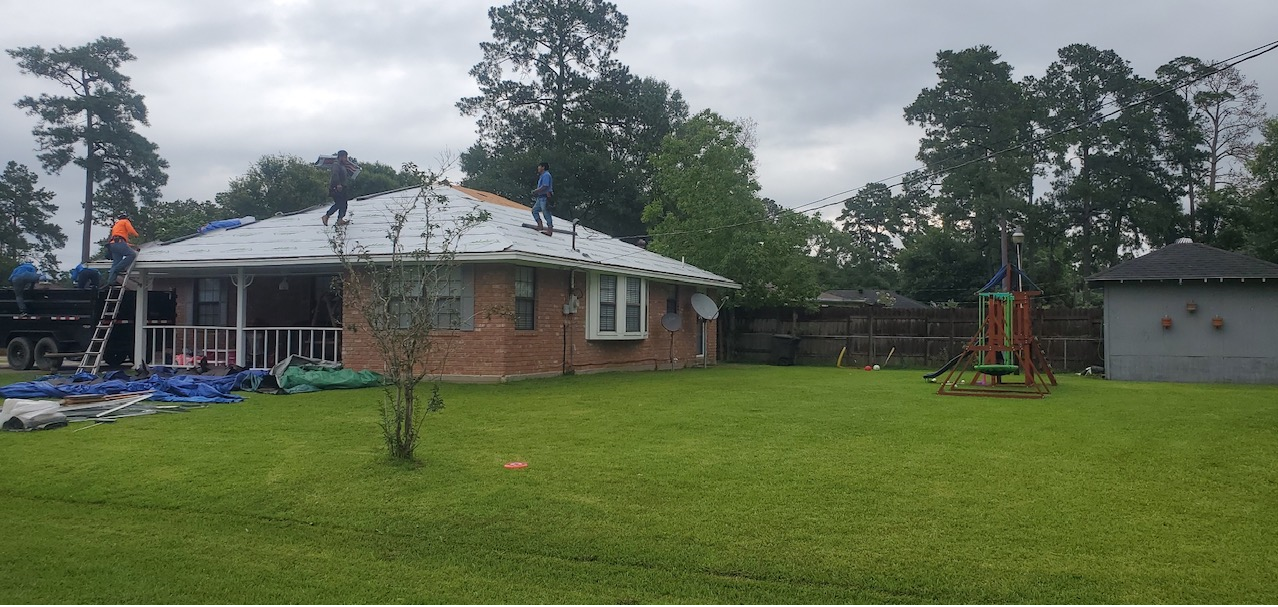 A brick house with a white roof is sitting on top of a lush green lawn.