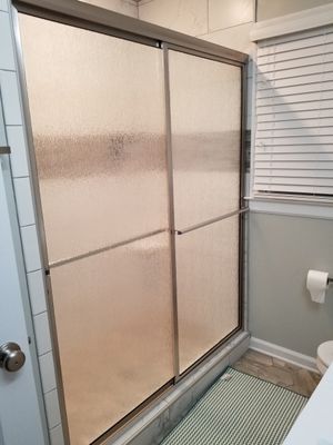 Shower enclosure with frosted glass sliding doors, stainless steel frame.