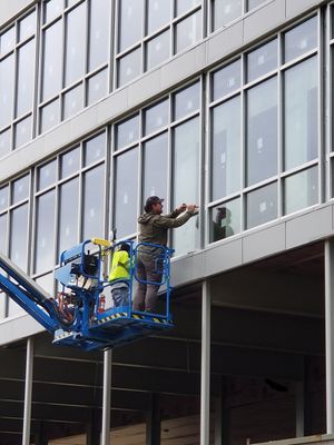 Workers in a lift installing windows on a modern building.