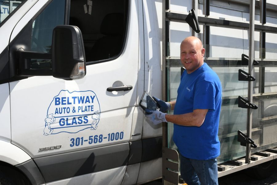 Man cleaning glass next to a van labeled 