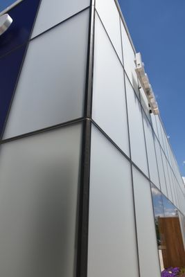 Modern building exterior with white panels outlined by black frames against a blue sky.