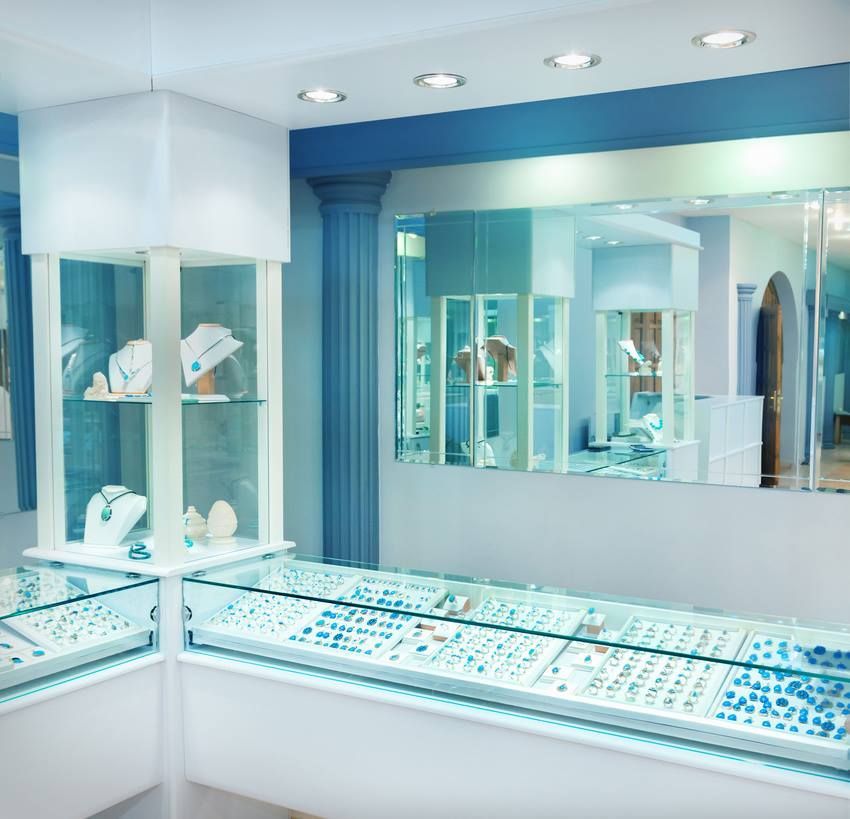 Jewelry store interior with glass display cases, filled with jewelry, and a large mirror.