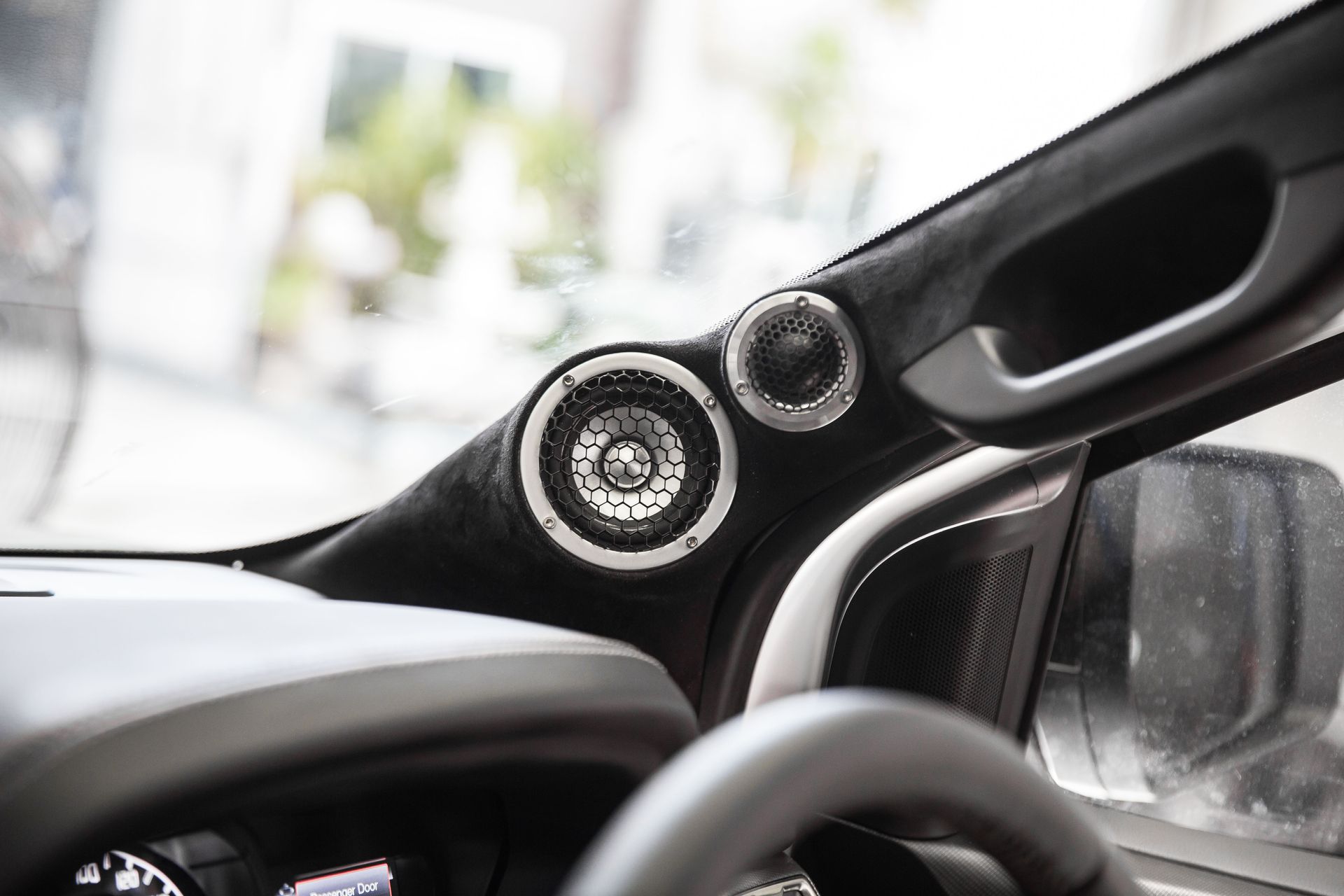 A close up of a car dashboard with speakers and a steering wheel.