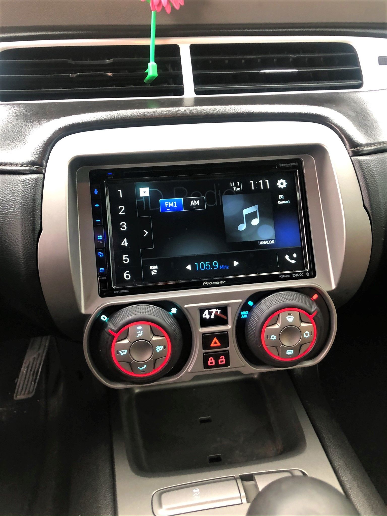 The dashboard of a car with a radio and a flower on top of it.