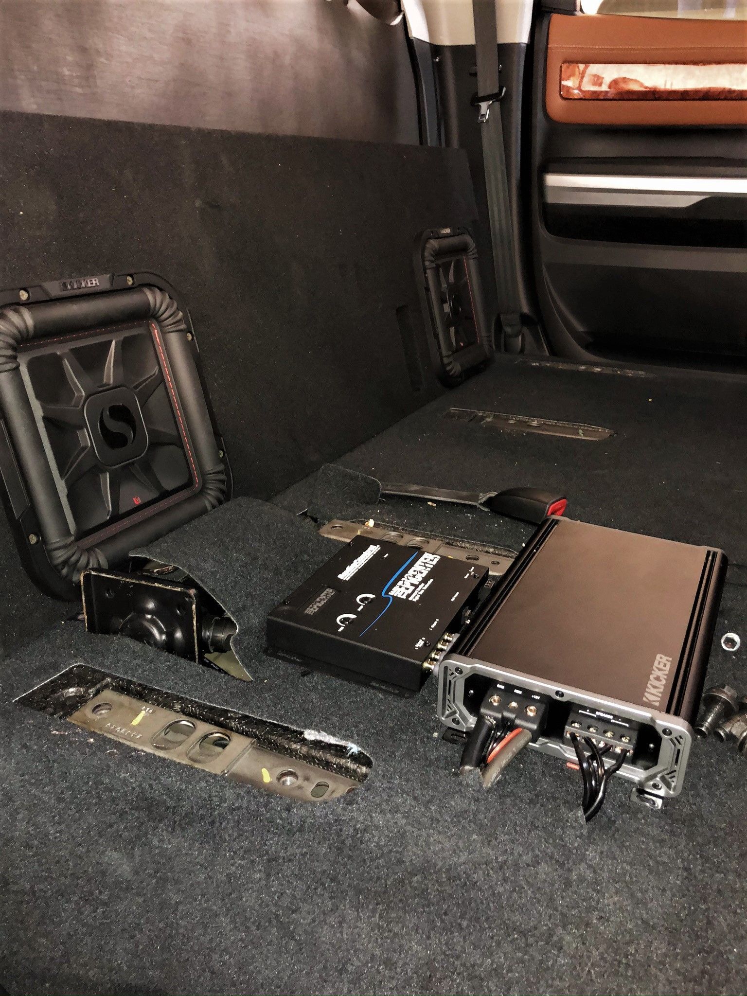 A subwoofer and amplifier are sitting in the back of a truck.