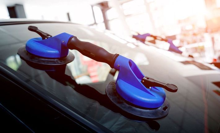 Blue suction cup tool on a car windshield, likely for removing or installing glass.