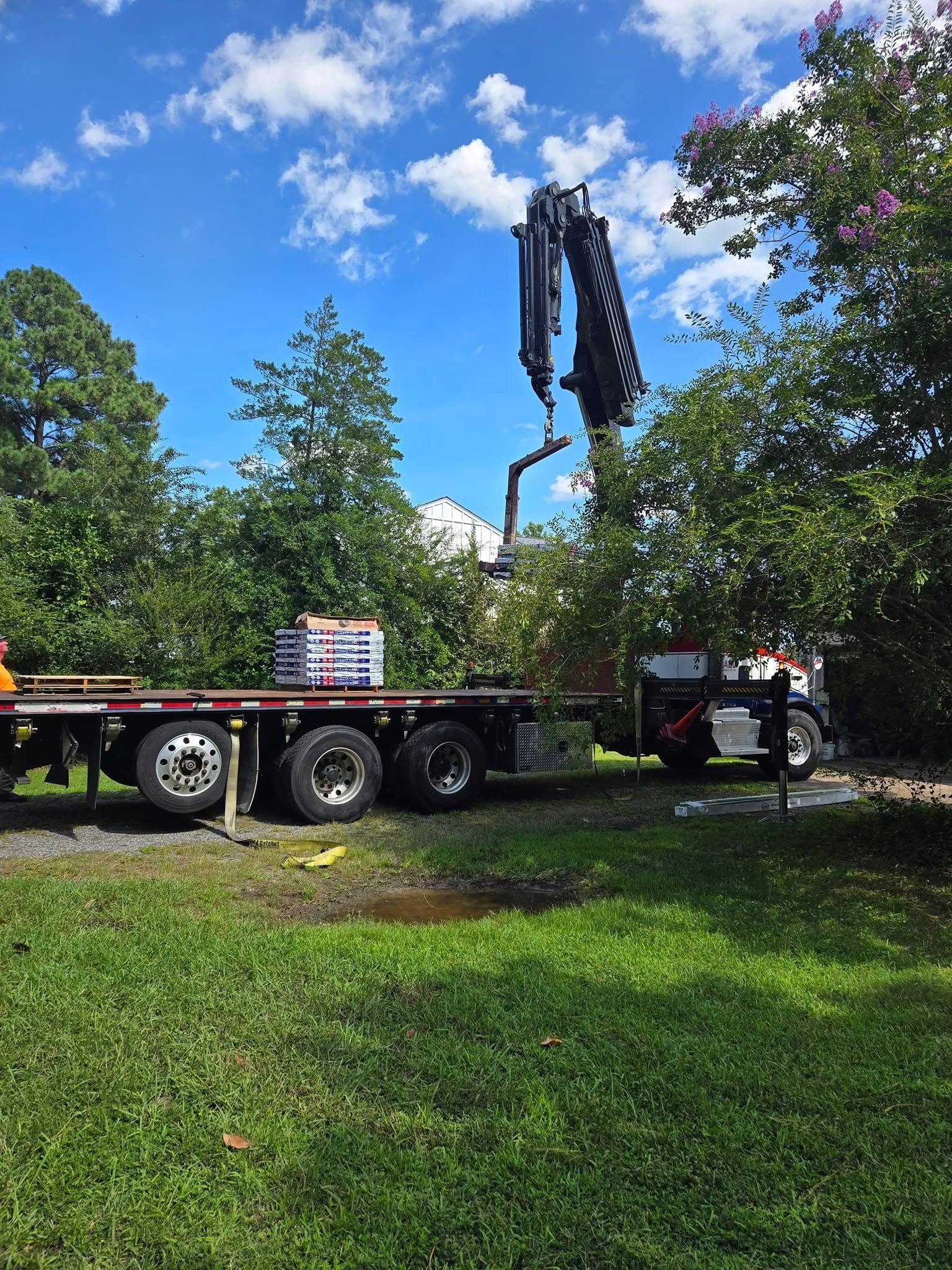 A truck with a crane on the back of it is parked in a grassy field.
