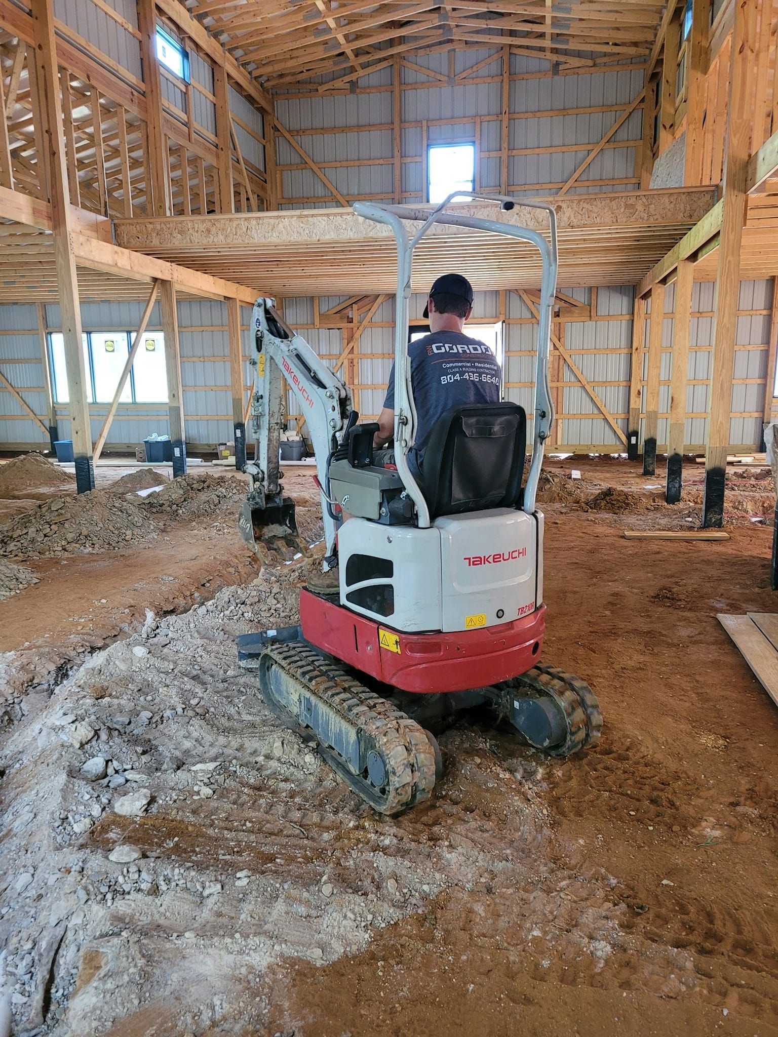 A man is driving a small excavator in a building under construction.