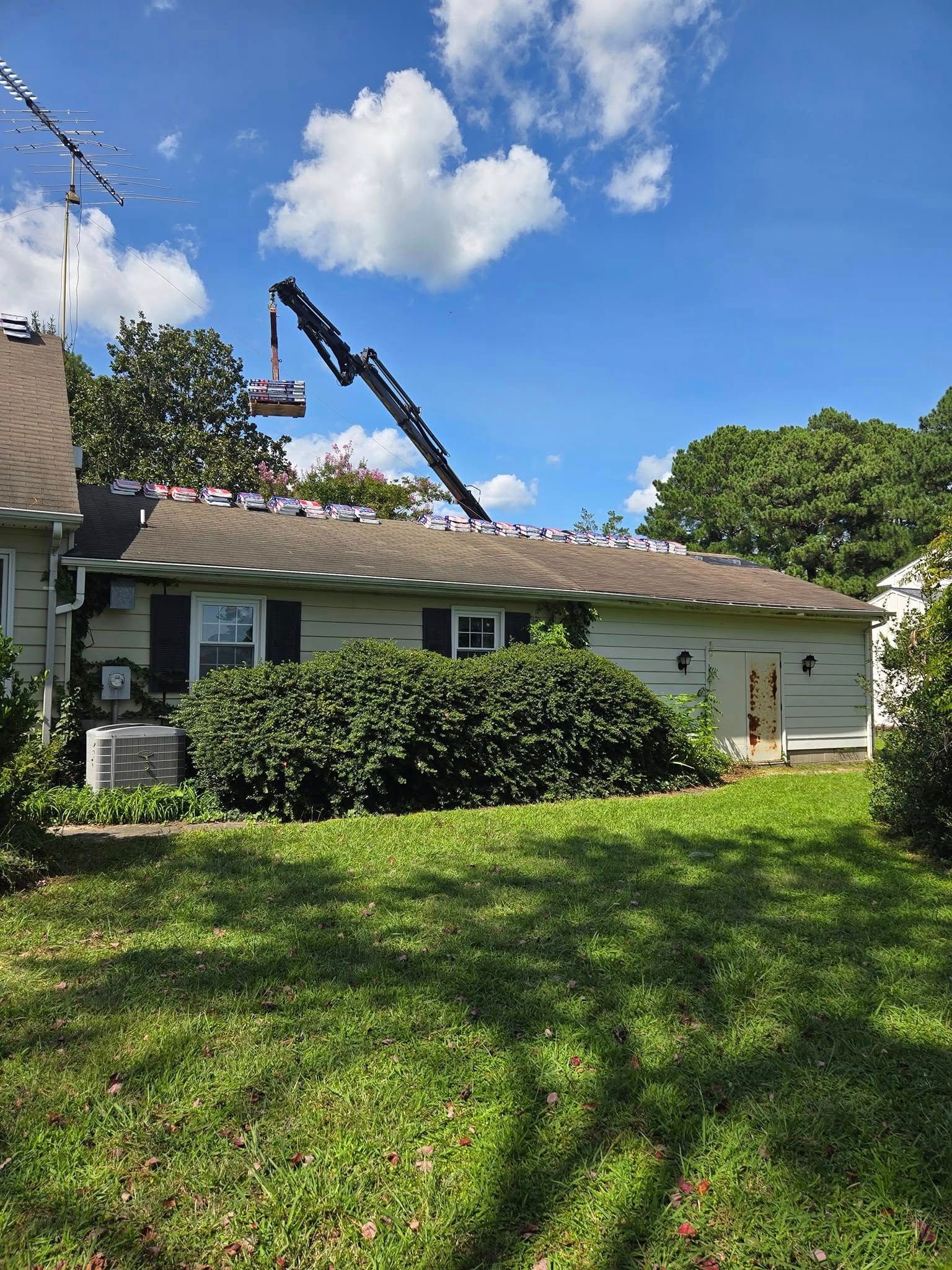 A crane is lifting a roof on a house.