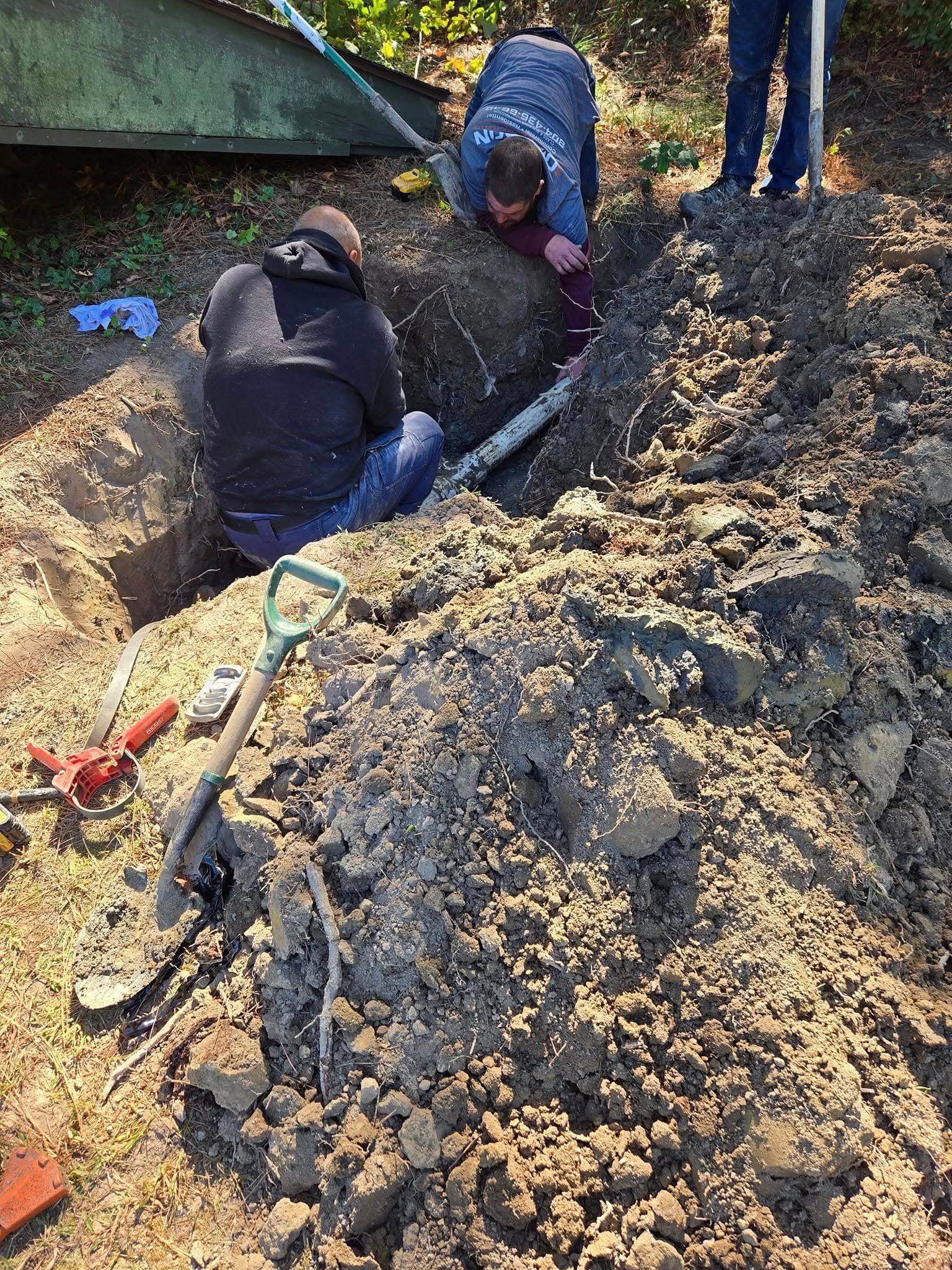 Two men are digging in the dirt with shovels.