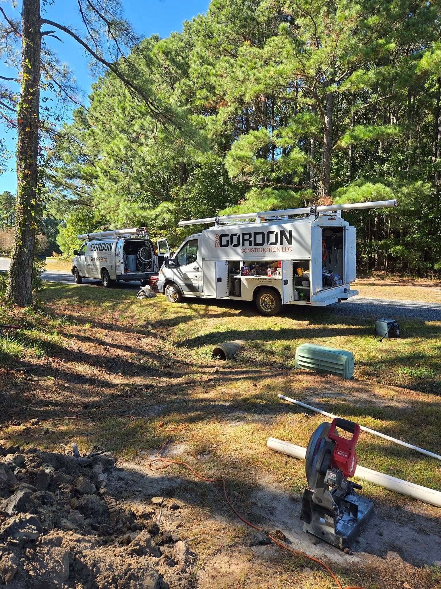 A man is cutting a pipe with a circular saw in front of a truck.