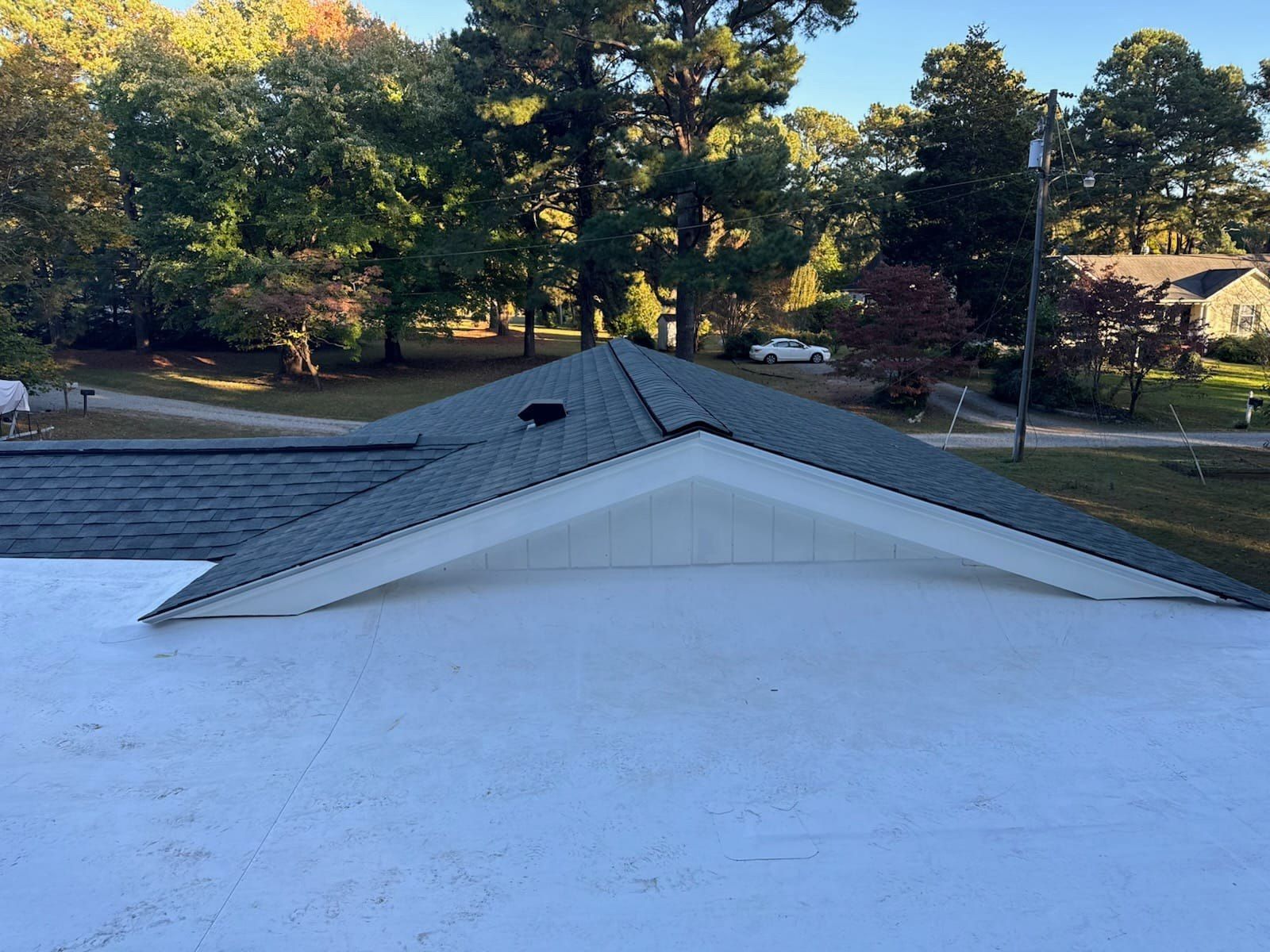 The roof of a house with a white roof and trees in the background