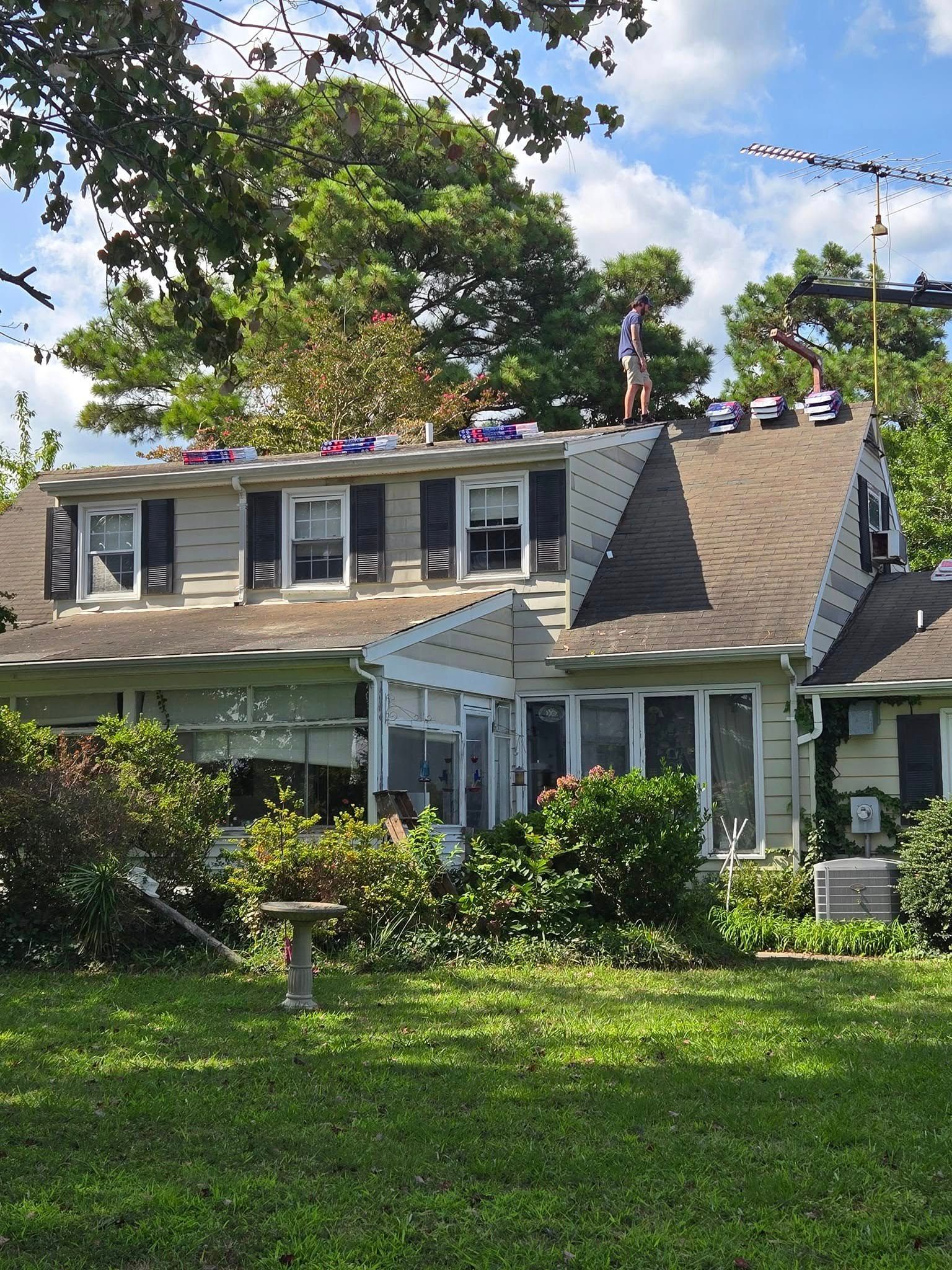 A man is standing on the roof of a house.