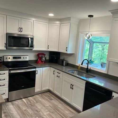 A kitchen with white cabinets, stainless steel appliances, a sink, and a window.