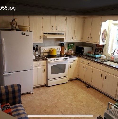 A kitchen with white cabinets and a white refrigerator