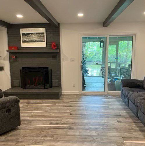 A living room with a fireplace, a couch, a chair, and a sliding glass door.