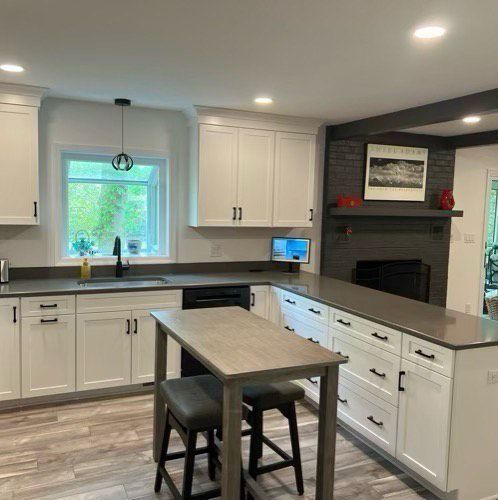 A kitchen with white cabinets, a table, and stools.
