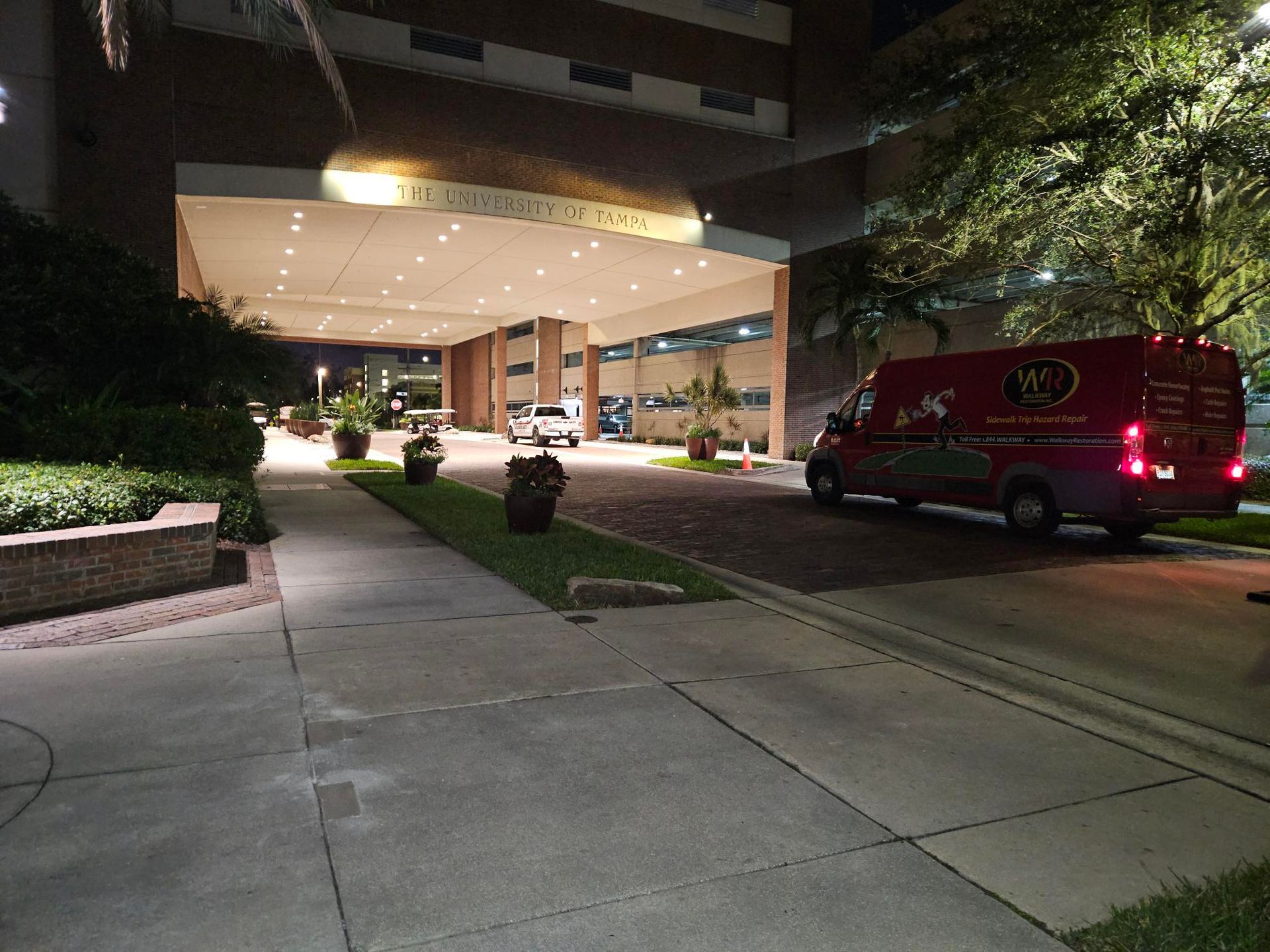 A red van is parked in front of a building at night