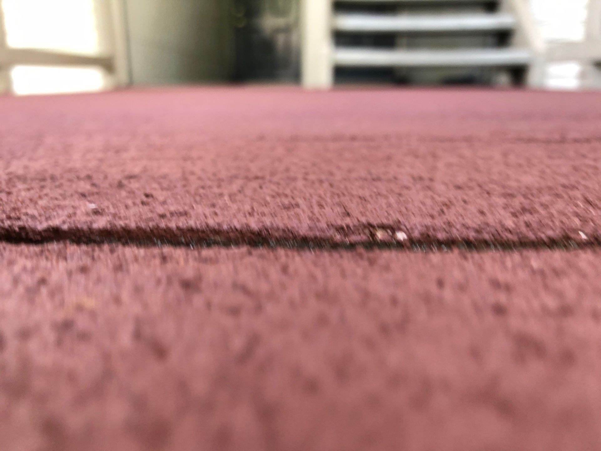 A close up of a red carpet with a staircase in the background.