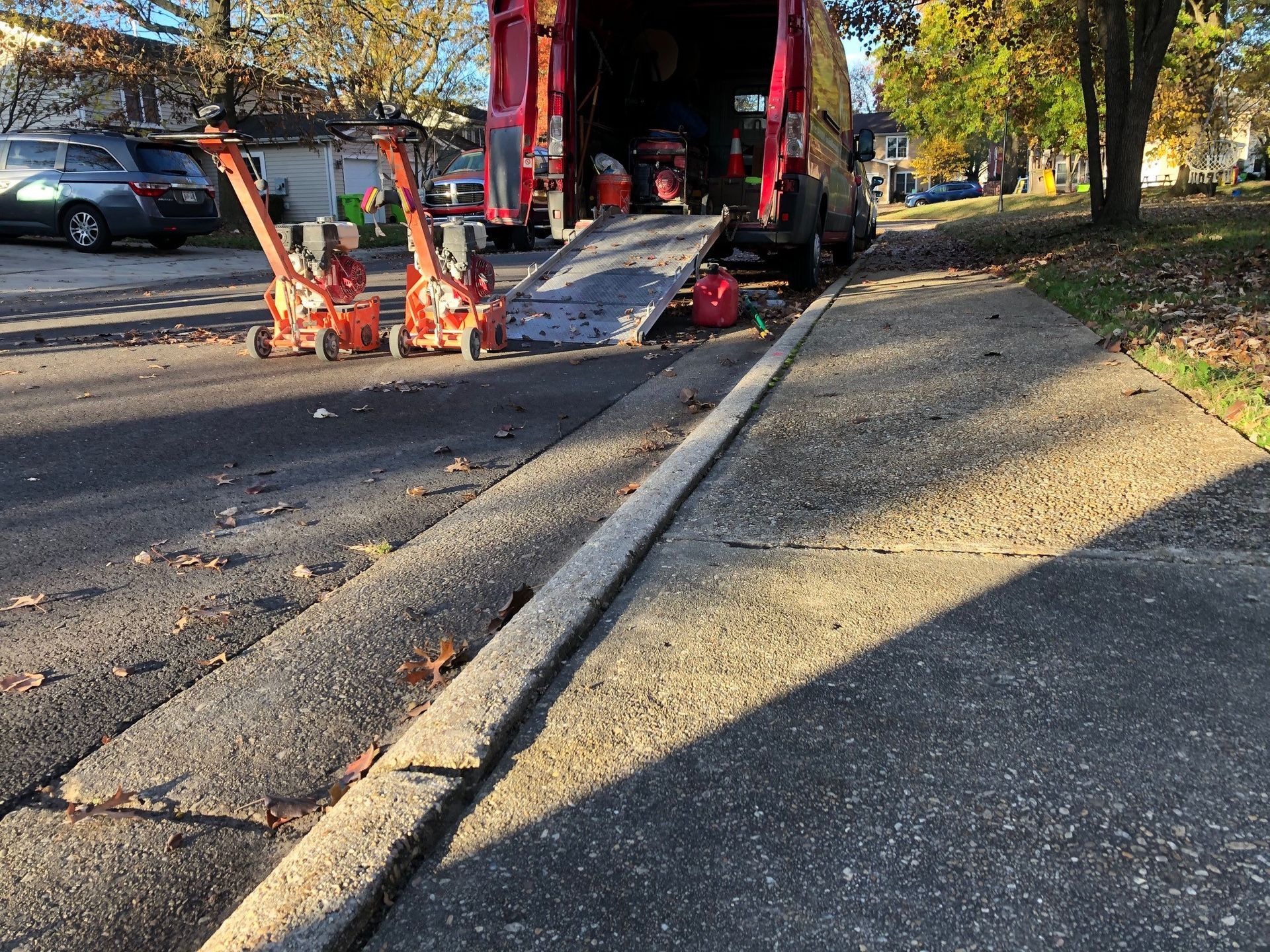 A red van with a ramp is parked on the side of the road.