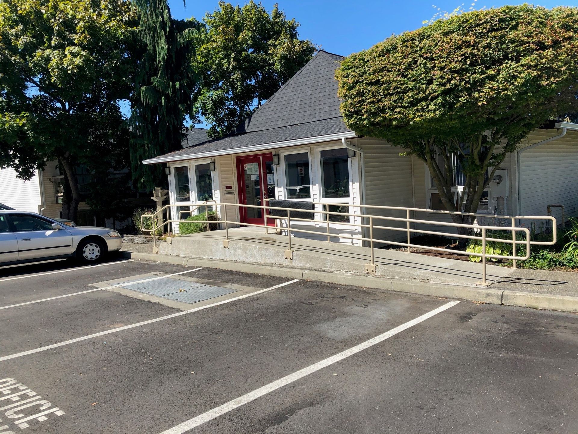 A white car is parked in a parking lot in front of a building.