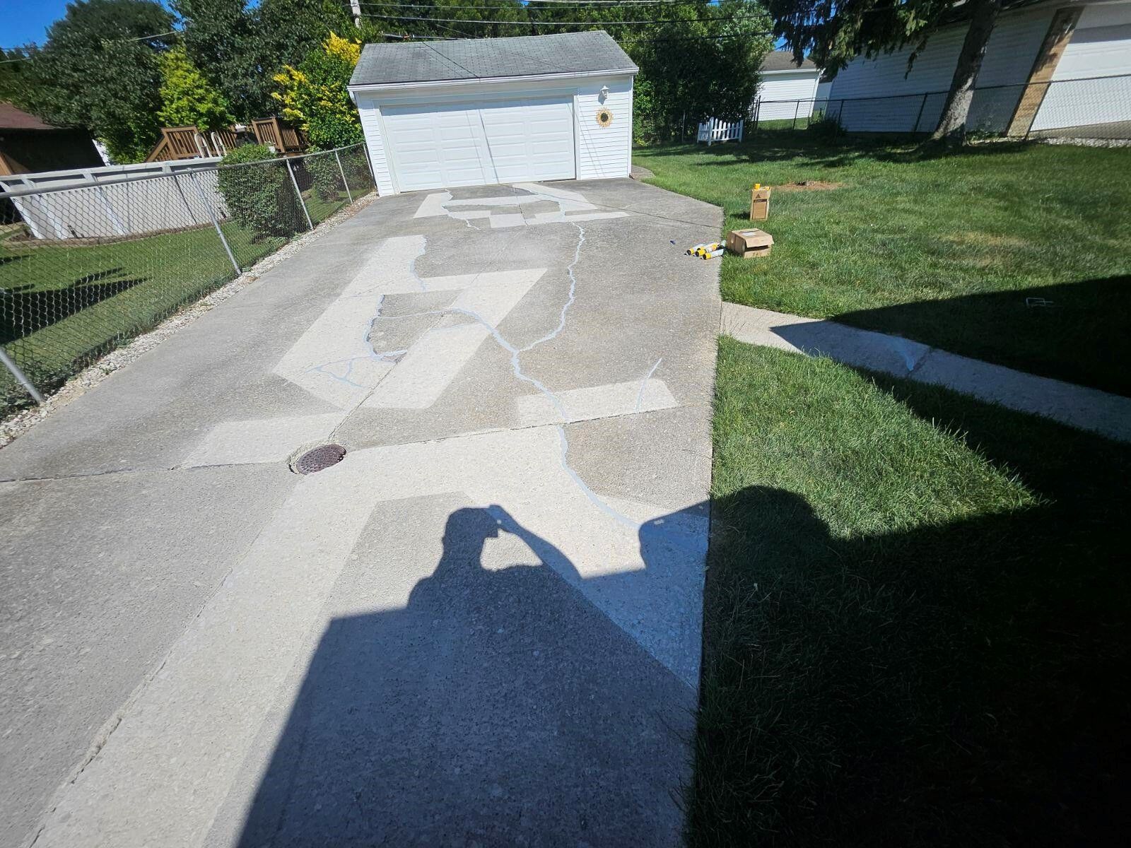 A person is taking a picture of their shadow on a driveway.
