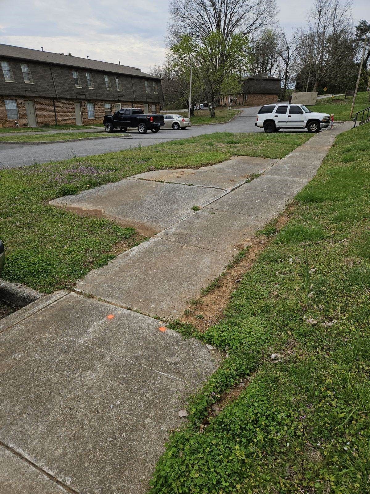 A white truck is parked on the side of the road next to a sidewalk.