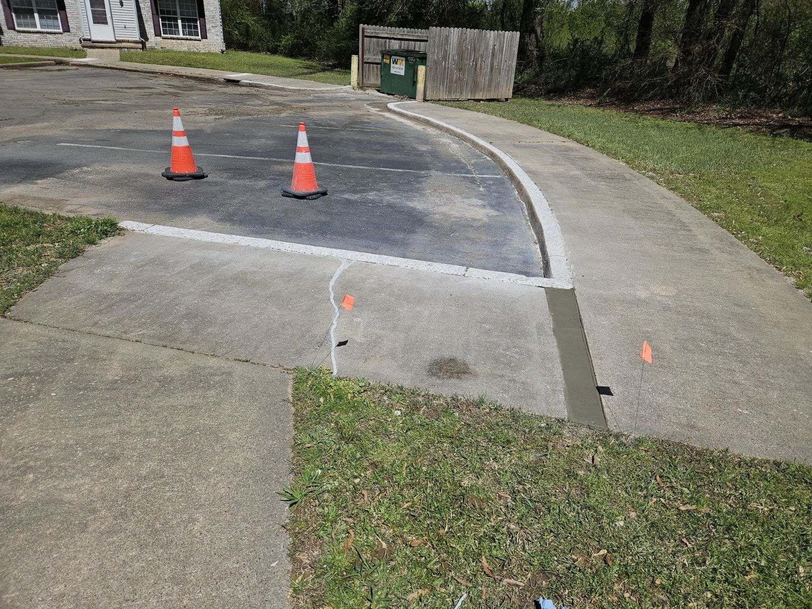 Two orange and white traffic cones are sitting on the sidewalk.