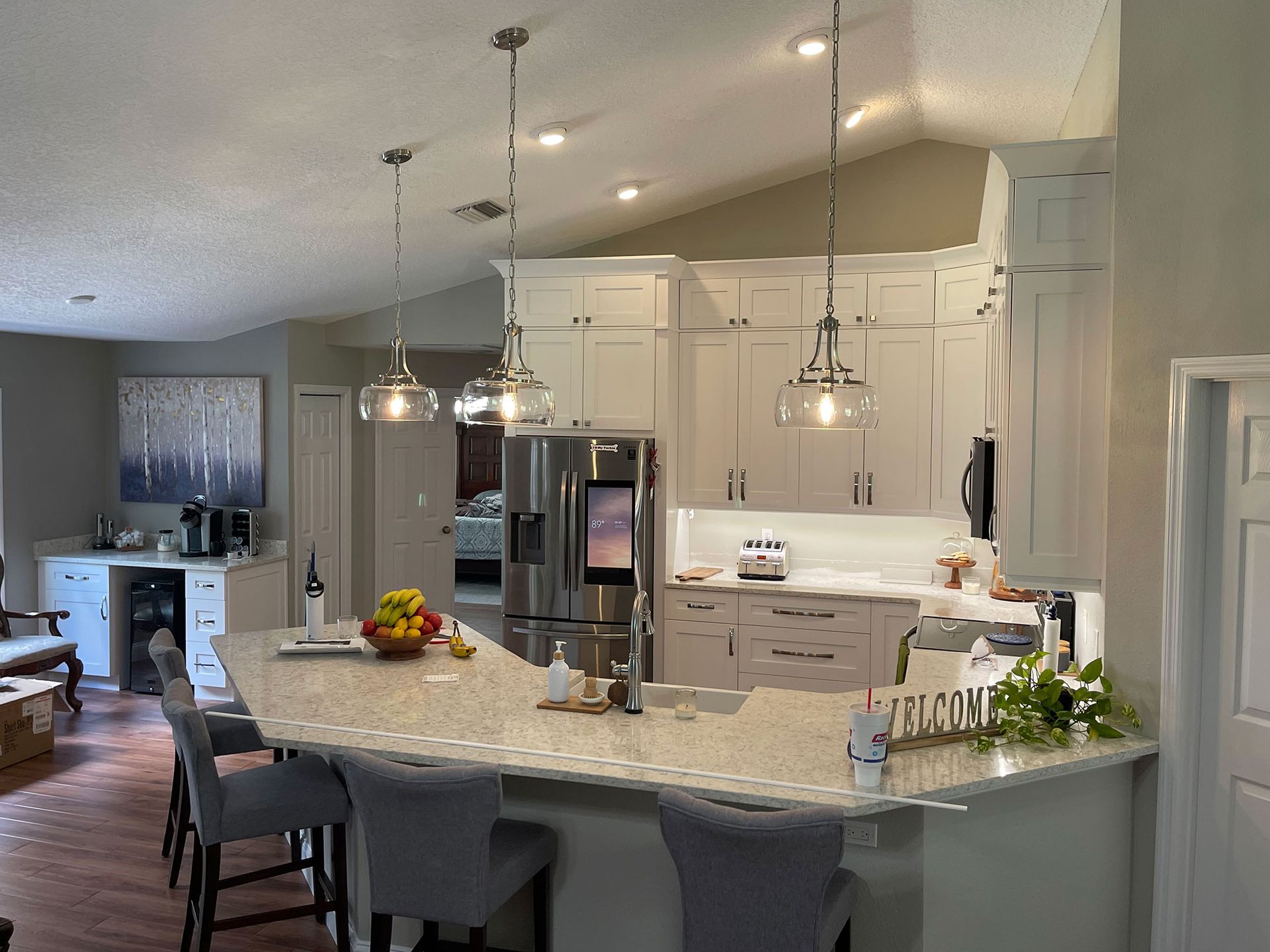 Modern kitchen with a curved marble island, pendant lights, and stainless steel appliances